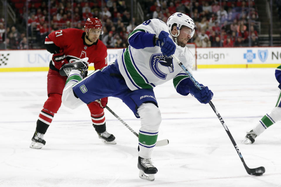 Vancouver Canucks center J.T. Miller (9) shoots on goal while Carolina Hurricanes right wing Nino Niederreiter (21), of Switzerland, looks on during the first period of an NHL hockey game in Raleigh, N.C., Sunday, Feb. 2, 2020. (AP Photo/Gerry Broome)