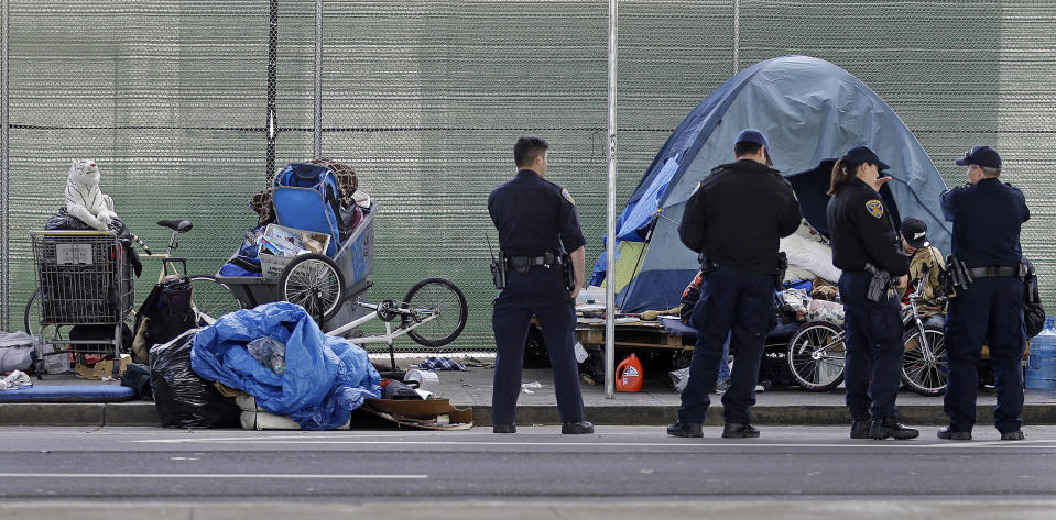 San Francisco police officers wait while homeless people collect their belongings in San Francisco in 2016.