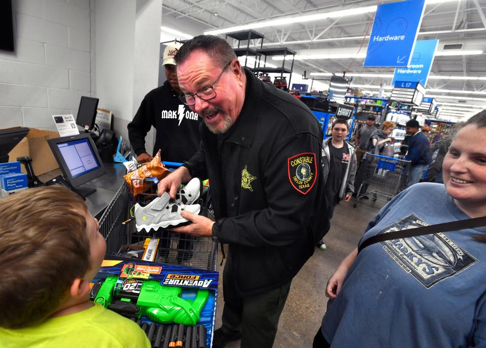 Taylor County Constable Jay Strong helps a boy with his gifts during Operation Brown Bag Tuesday at the Southwest Drive Walmart. The Christmas program was started in 2017 by Strong when he was the Tye police chief.