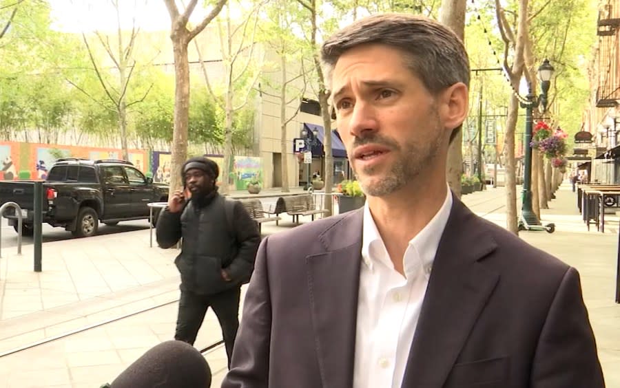 Mayor Matt Mahan speaks on camera while a man approaches in the background on April 23, 2024. (KRON4 Photo)