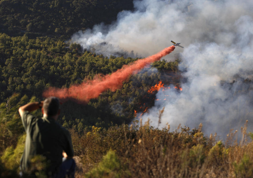 A plane drops fire retardant over a forest fire on Mount Carmel near the northern city of Haifa December 4, 2010. International firefighting teams were helping Israel battle a huge forest fire close to the port of Haifa which has killed at least 42 people and forced mass evacuations.  REUTERS/Amir Cohen   (ISRAEL - Tags: ENVIRONMENT DISASTER)