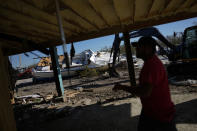 Contractors work to clear debris from the wreckage of Getaway Marina where owner Robert Leisure (not pictured) has begun the long process of rebuilding his business after the passage of Hurricane Ian, on San Carlos Boulevard in Fort Myers Beach, Fla., Sunday, Oct. 2, 2022. (AP Photo/Rebecca Blackwell)