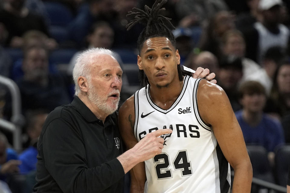 San Antonio Spurs head coach Gregg Popovich, left, talks with guard Devin Vassell (24) during the first half of an NBA basketball game against the Orlando Magic, Thursday, Feb. 8, 2024, in Orlando, Fla. (AP Photo/John Raoux)