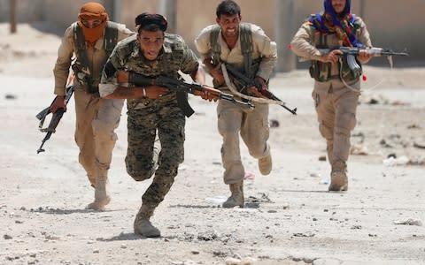 Kurdish fighters from the People's Protection Units (YPG) run across a street in Raqqa during the offensive against Isil - Credit: Reuters