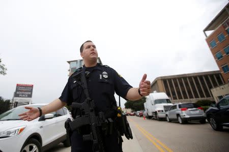 A Dallas police officer moves media away from in front of the Dallas Police Department headquarters which was locked down after an anonymous threat was reported in Dallas, Texas, U.S. July 9, 2016. REUTERS/Carlo Allegri