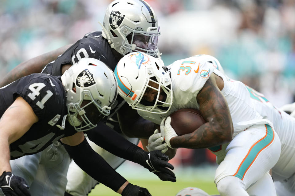 Miami Dolphins running back Raheem Mostert (31) is tackled by Las Vegas Raiders linebacker Robert Spillane (41) and defensive tackle Bilal Nichols (91) during the second half of an NFL football game, Sunday, Nov. 19, 2023, in Miami Gardens, Fla. (AP Photo/Rebecca Blackwell)