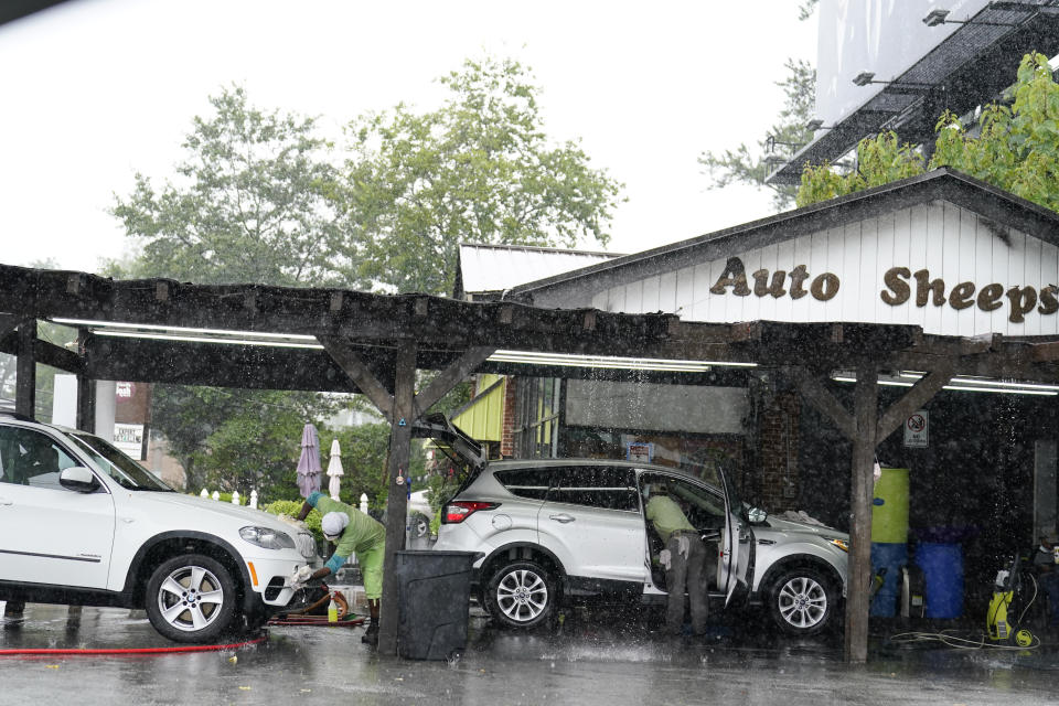 People wash and dry cars near Atlanta, while Tropical Storm Fred makes its way through north and central Georgia on Tuesday, Aug. 17, 2021. (AP Photo/Brynn Anderson)