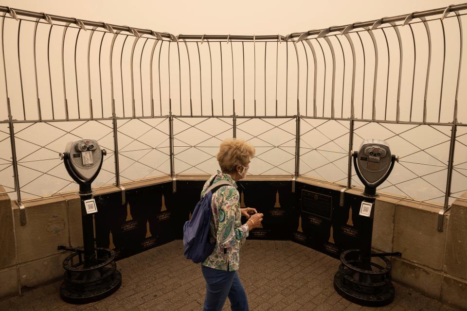 A person wearing a face mask views New York City in a haze-filled sky from the Empire State Building observatory, Wednesday, June. 7, 2023, in New York.