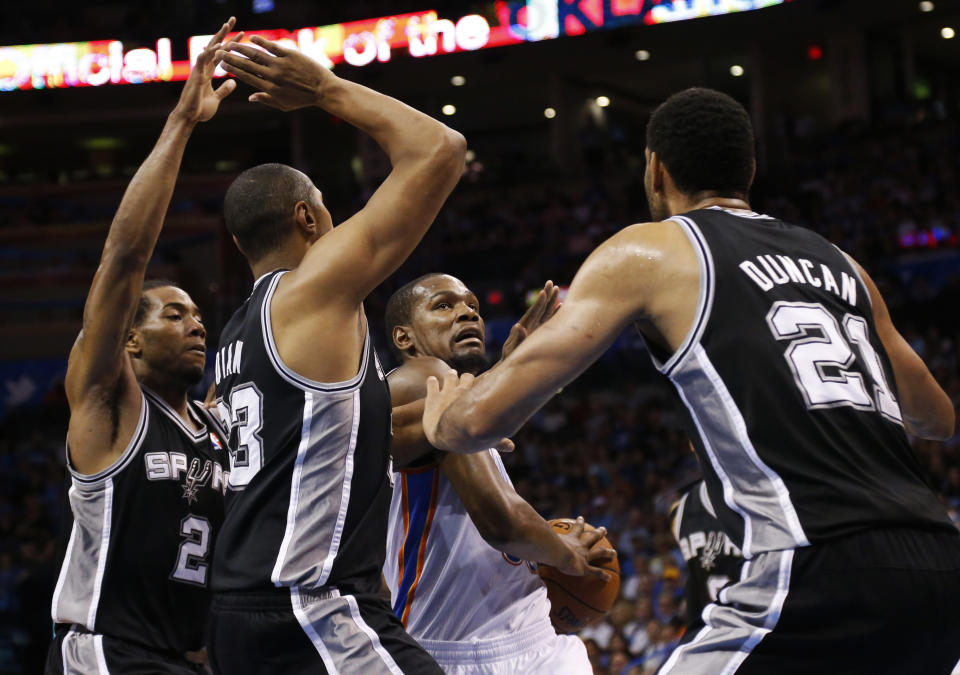 Oklahoma City Thunder forward Kevin Durant (35) attempts to drive between San Antonio Spurs forwards Kawhi Leonard (2), Boris Diaw (33), and Tim Duncan (21) during the first quarter of an NBA basketball game in Oklahoma City, Thursday, April 3, 2014. (AP Photo/Sue Ogrocki)