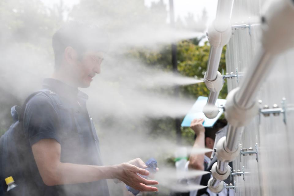 A man cools off at a mist station installed at Shiokaze Park during the beach volleyball test event for the Tokyo 2020 Olympic Games in Tokyo on July 25, 2019. - Tokyo 2020 Olympics organisers tested everything from misting sprays to air-conditioned tents on July 25 as they trialed heat mitigation measures a year before the Games gets under way. (Photo by Behrouz MEHRI / AFP)        (Photo credit should read BEHROUZ MEHRI/AFP/Getty Images)