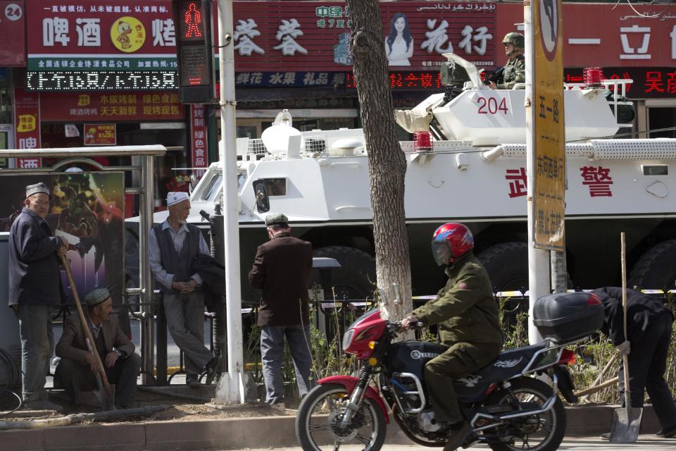 Uighur men rest from shoveling dirt near an Chinese paramilitary police armored personnel carrier on the streets of Urumqi in northwest China's Xinjiang Uygur Autonomous Region on Thursday May 1, 2014. Recent deadly attacks in China blamed on Islamic extremists are getting bolder and bloodier, targeting civilians rather than the authorities and further challenging Beijing’s ability to stop them. (AP Photo/Ng Han Guan)