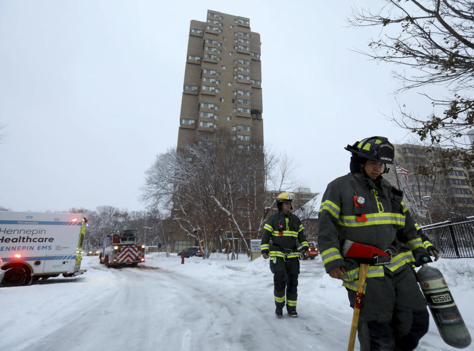 Minneapolis firefighters leave after a deadly fire at a high-rise apartment building, in background, Wednesday, Nov. 27, 2019, in Minneapolis. (David Joles/Star Tribune via AP)