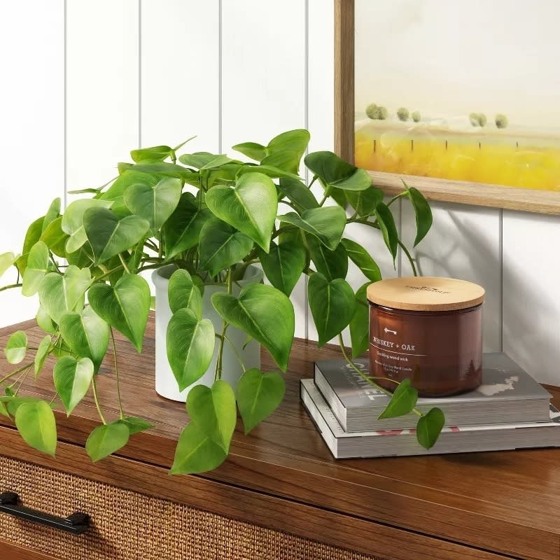 the faux plant on a counter next to a candle