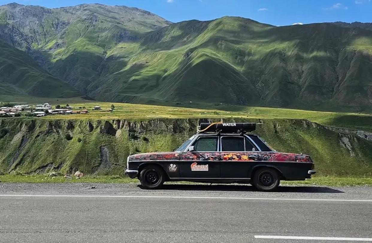 A classic Mercedes Benz W115 against the backdrop of mountains in Georgia.