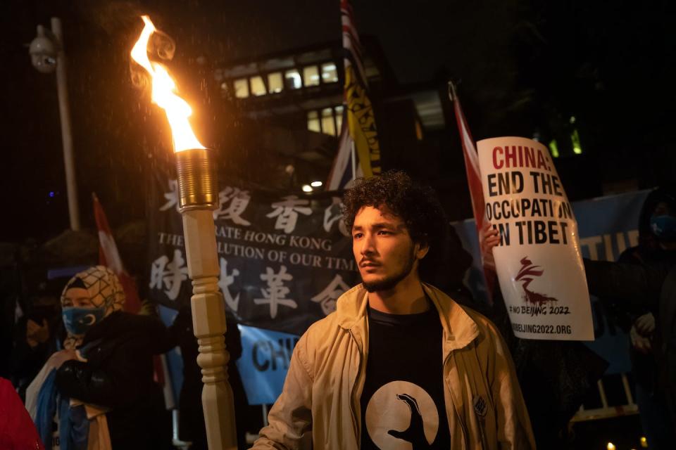 A Uyghur man who immigrated to Canada in 2007 with his parents holds a homemade torch during a protest against the Beijing Winter Olympics outside the Chinese consulate in Vancouver in February 2022. THE CANADIAN PRESS/Darryl Dyck