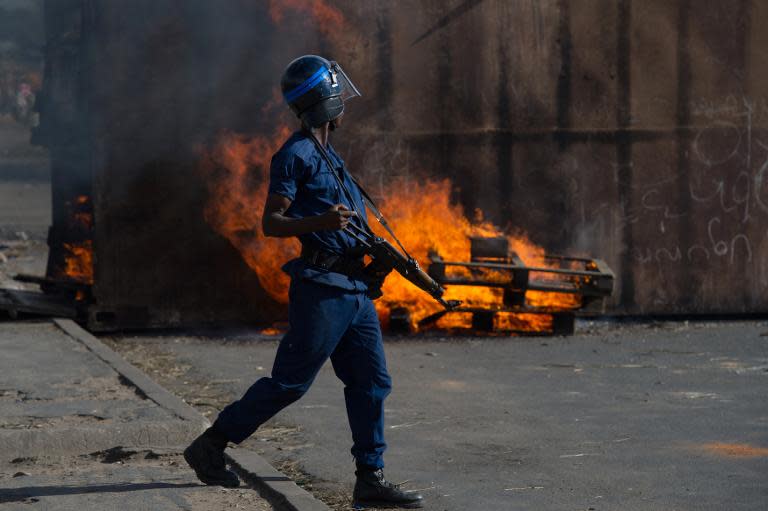A Burundi police officer walks past a burning barricade in the Cibitoke neighbourhood of Bujumbura, on May 5, 2015