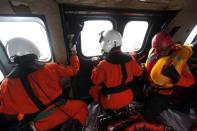 Indonesian Air Force crew and rescuers look out the windows of a Super Puma helicopter during a search and rescue operation for AirAsia flight QZ8501, over Kumai Bay, south of Pangkalan Bun, Central Kalimantan January 4, 2015. REUTERS/Adi Weda/Pool