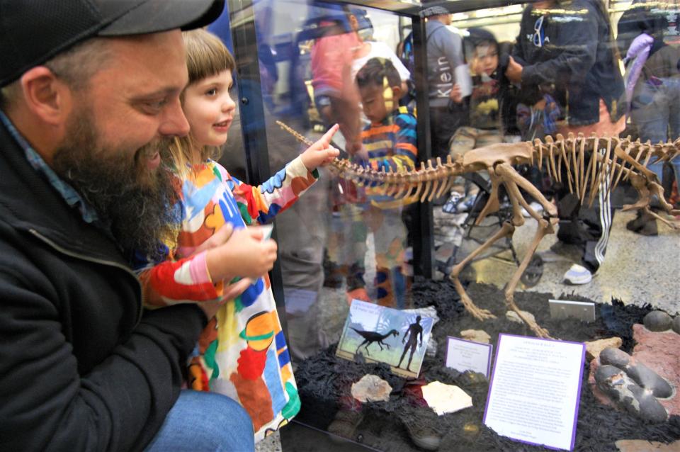 Sean Dugan and his daughter Ruby examine the fossilized oviraptor eggs and nest Dugan's family donated to the Sherman Dugan Museum of Geology at the San Juan College School of Energy during an unveiling ceremony Tuesday, Nov. 15 in Farmington.
