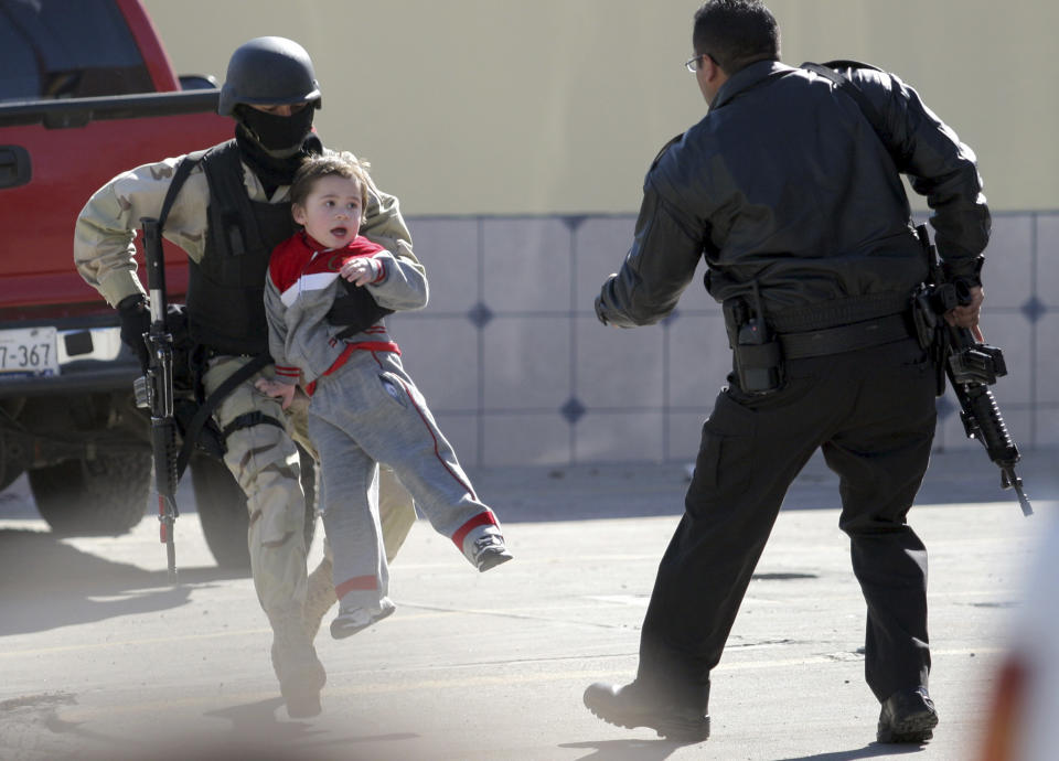 Un policía trata de poner a salvo a un niño durante una balacera en Tijuana, Baja California, México. REUTERS/Jorge Duenes