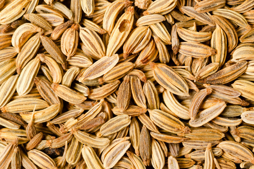 A close-up shot of several fennel seeds scattered across a flat surface