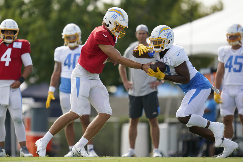 Los Angeles Chargers quarterback Justin Herbert (10) and running back Isaiah Spiller (28) participate in drills at the NFL football team's practice facility in Costa Mesa, Calif. Monday, Aug. 1, 2022. (AP Photo/Ashley Landis)
