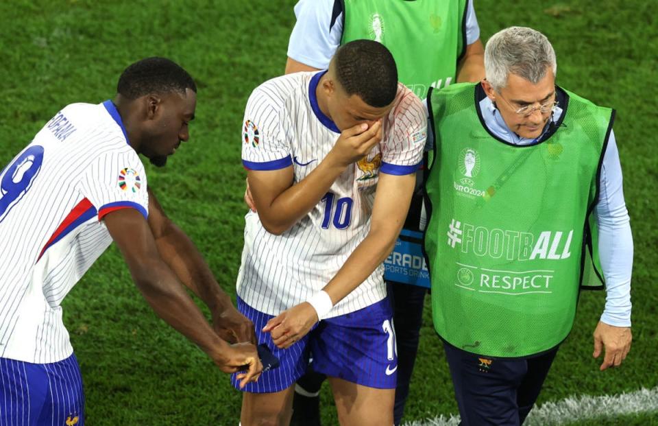 Mbappe covered his nose as he was helped off the pitch (Getty Images)
