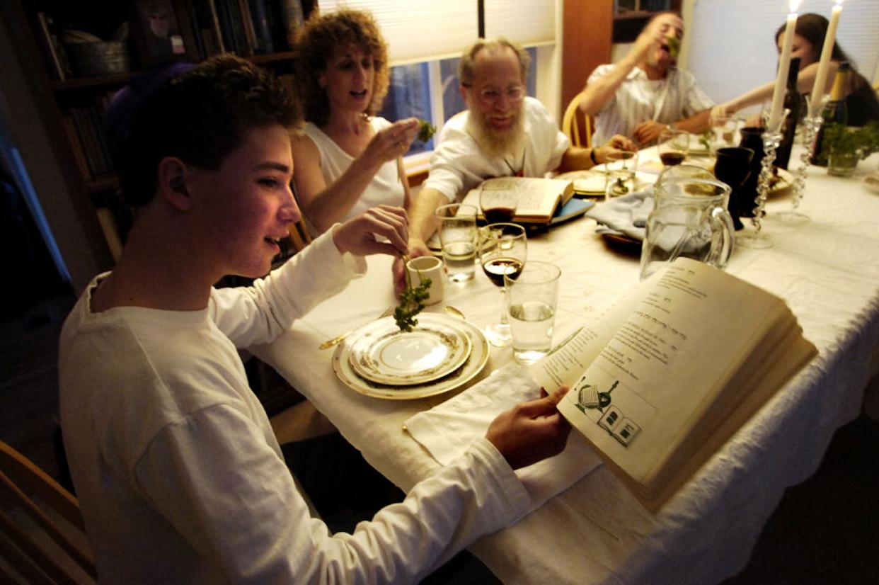 Amitai Gross reads from the Haggadah while preparing to dip parsley into salt water as part of the Passover meal, called the Seder. <a href="https://www.gettyimages.com/detail/news-photo/amitai-gross-left-reads-from-the-haggadah-a-jewish-holiday-news-photo/1089892414?adppopup=true" rel="nofollow noopener" target="_blank" data-ylk="slk:Marty Caivano/Digital First Media/Boulder Daily Camera via Getty Images;elm:context_link;itc:0;sec:content-canvas" class="link ">Marty Caivano/Digital First Media/Boulder Daily Camera via Getty Images</a>