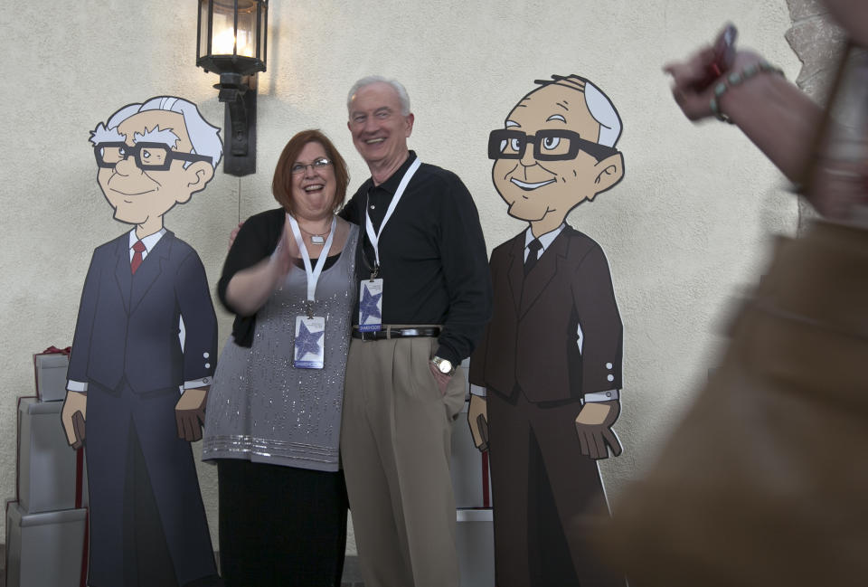 Shareholders pose with cardboard cartoons of Berkshire Hathaway chairman and CEO Warren Buffett, left, and his vice chairman Charlie Munger outside the Berkshire-owned Borsheims jewelry store in Omaha, Neb., Friday, May 4, 2012. Berkshire Hathaway is expected to have 30,000 shareholders come to Omaha for it's annual shareholders meeting this weekend. (AP Photo/Nati Harnik)
