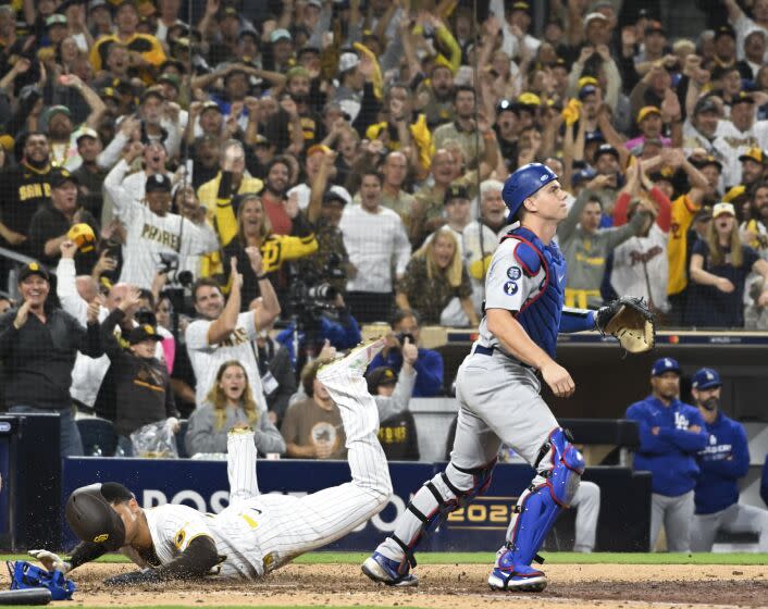 Th Padres' Juan Soto dives to score as Dodgers catcher Will Smith looks on in the seventh inning Oct. 15, 2022.