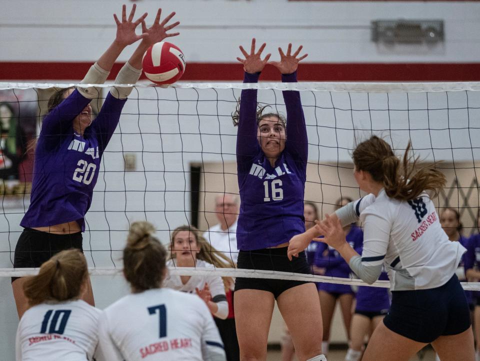 Louisville Male High's Taylor McBride, #20, and Chloe Osborne, #16, rise up to block a shot by Sacred Heart's Tess Schrenger, right, during the 7th region volleyball finals. Oct. 28, 2021