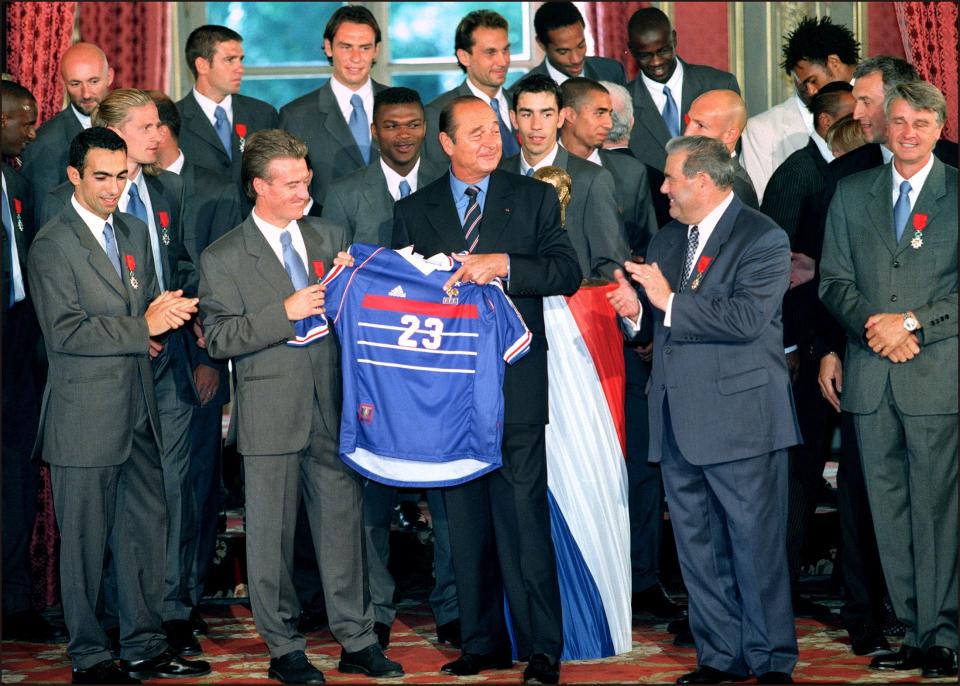 le président Jacques Chirac (C) brandit le maillot tricolore, que vient de lui offrir le capitaine de l'Equipe de France de football, Didier Deschamps (2e G), le 01 septembre au Palais de l'Elysée à Paris, lors de la cérémonie organisée en l'honneur de la sélection des 22 joueurs de l'équipe de France, victorieuse de la Coupe du Monde. (Photo by Gabriel BOUYS / AFP)        (Photo credit should read GABRIEL BOUYS/AFP/Getty Images)