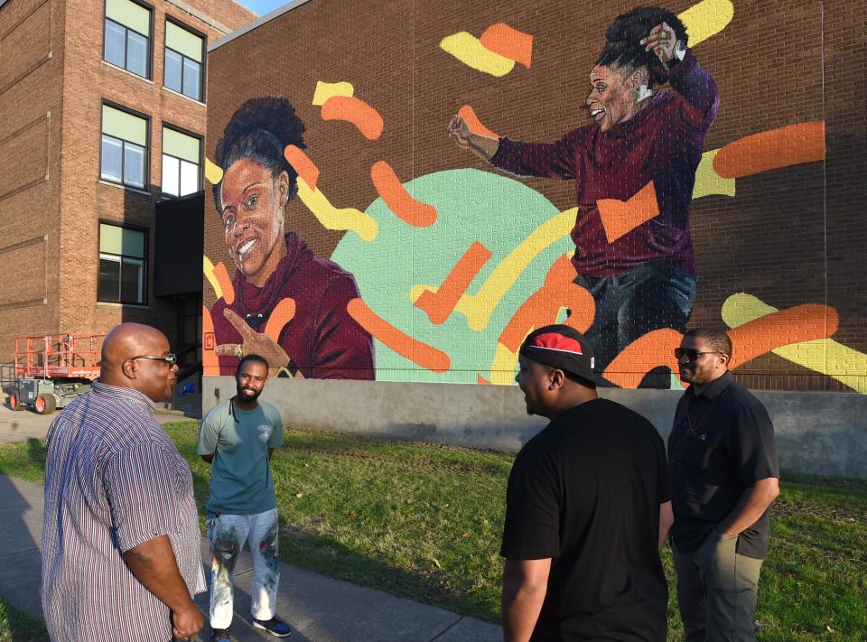 From left, Joe Hughes of Erie meets with artists Mwanel Pierre-Louis of Miami, Florida, Brian Bonner and Antonio Howard, both of Erie, on Sept. 27 outside the former Wayne School. The artists created a mural of Joe Hughes’ sister, Carla Hughes.