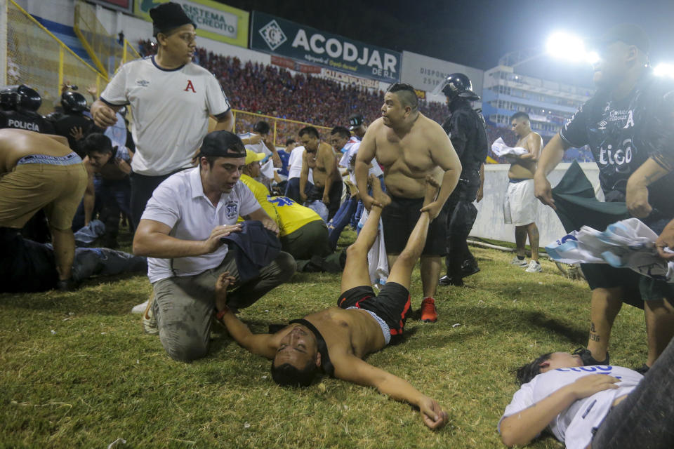 Soccer fans are assisted by others fans at the field of the Cuscatlan stadium in San Salvador, El Salvador, Saturday, May 20, 2023. At least nine people were killed and dozens more injured when stampeding fans pushed through one of the access gates at a quarterfinal Salvadoran league soccer match between Alianza and FAS. (AP Photo/Milton Flores)