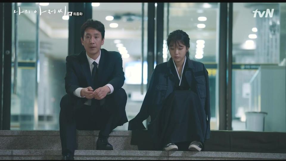 a man and a woman sit next to each other in front of glass doors