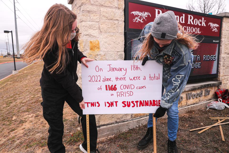 Round Rock school district students place signs outside Round Rock High School on Thursday to demand tougher COVID-19 safety measures.