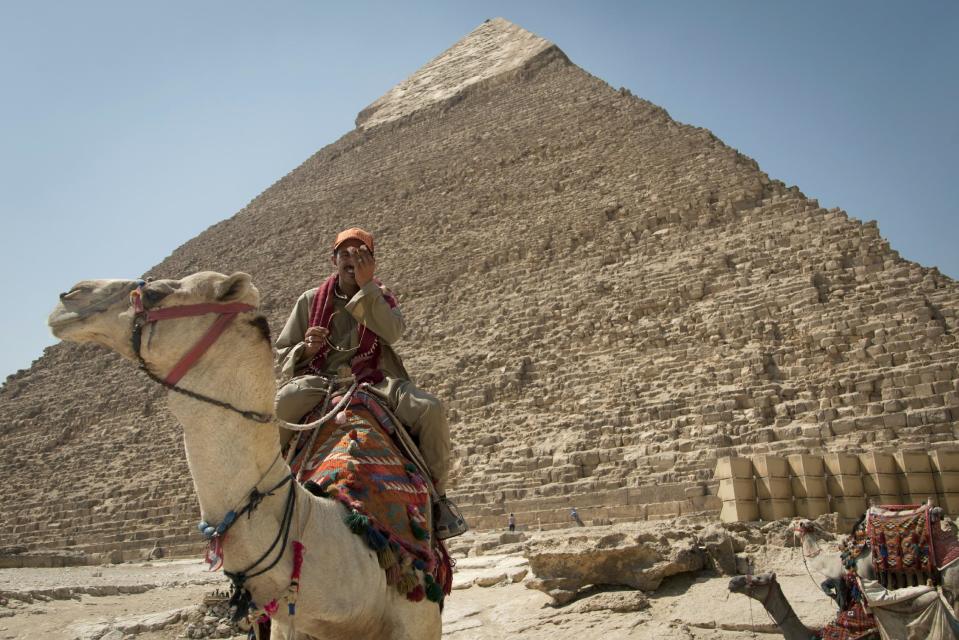 In this Thursday, Sept. 27, 2012 photo, a tour guide sits on his camel as he waits for clients next to the Giza pyramids, near Cairo, Egypt. The Egyptian demonstrations against an online film that was produced by a U.S. citizen originally from Egypt and denigrates the Prophet Muhammad were part of a wider explosion of anger in Muslim countries. They happened near the U.S. Embassy, far from the pyramids of Giza on Cairo's outskirts, and a lot further from gated Red Sea resorts, cocoons for the beach-bound vacationer. Yet the online or TV images _ flames, barricades, whooping demonstrators _ are a killjoy for anyone planning a getaway, even though the protests have largely subsided. Tour guides in Egypt say tourist bookings are mostly holding, but they worry about a dropoff early next year, since people tend to plan several months ahead.(AP Photo/Khalil Hamra)