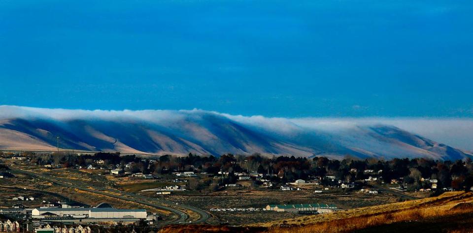 Low clouds roll over the Horse Heaven Hills in Badger Canyon behind the Rancho Reata housing development and west toward Benton City.