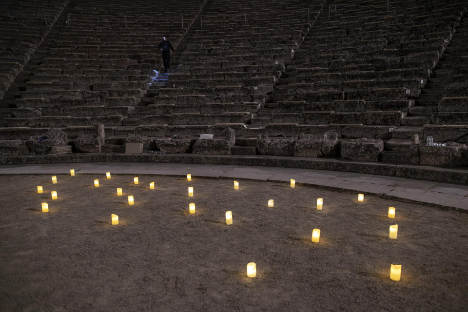 A man with a flashlight goes down the stairs of the ancient theater of Epidaurus after the end of a performance, early Saturday July 18, 2020. Live concerts and events have been mostly canceled in Greece this summer due to pandemic concerns. But the Culture Ministry allowed the ancient theaters of Epidaurus in southern Greece to host performances under strict safety guidelines. (AP Photo/Petros Giannakouris)