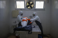 FILE - In this Sunday, May 10, 2020, file photo, female morgue workers, wearing suits, face masks and shield for protection against the coronavirus, prepare the body of a woman who died of COVID-19, at the Zincirlikuyu morgue in Istanbul, for burial according to Islamic traditions. When Turkey changed the way it reports daily COVID-19 infections, it confirmed what medical groups and opposition parties have long suspected — that the country is faced with an alarming surge of cases that is fast exhausting the Turkish health system. The official daily COVID-19 deaths have also steadily risen to record numbers in a reversal of fortune for the country that had been praised for managing to keep fatalities low. With the new data, the country jumped from being one of the least-affected countries in Europe to one of the worst-hit. (AP Photo/Emrah Gurel, File)