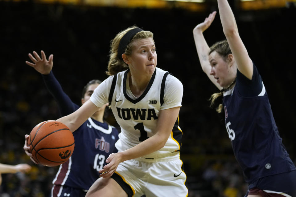 Iowa guard Molly Davis (1) passes around Fairleigh Dickinson forward Lilly Parke, right, during the second half of an NCAA college basketball game, Monday, Nov. 6, 2023, in Iowa City, Iowa. (AP Photo/Charlie Neibergall)