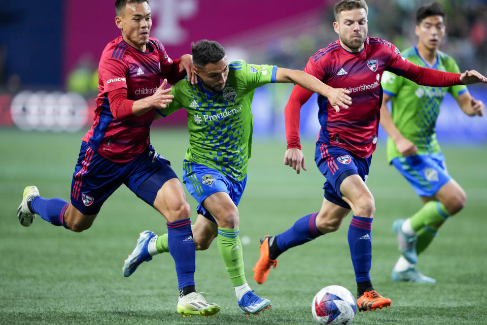 Seattle Sounders midfielder Cristian Roldan, second from left, drives the ball while pursued by FC Dallas defender Sam Junqua, left, and midfielder Asier Illarramendi, right, during the first half of Game 3 of a first-round playoff MLS soccer match Friday, Nov. 10, 2023, in Seattle. (AP Photo/Lindsey Wasson)