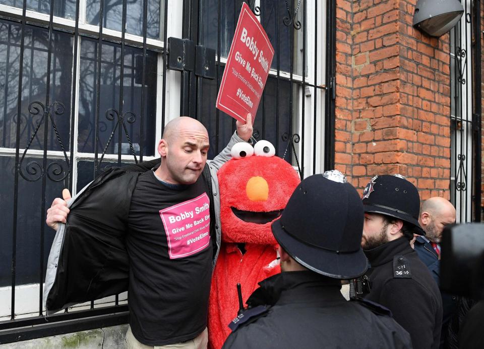 Police officers stand with British political and fathers' rights activist Bobby Smith with his sister dressed up as Elmo. (AFP via Getty Images)