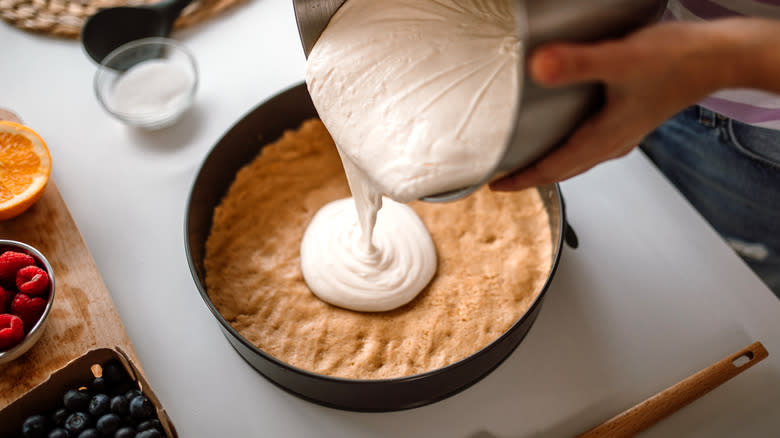 Pouring cheesecake filling into pan