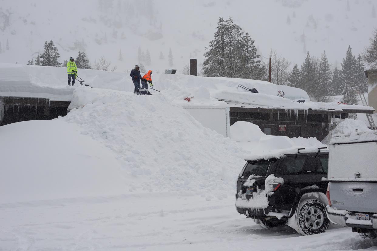 Workers clear snow off the roof of a building during a blizzard Sunday, March 3, 2024, in Olympic Valley, Calif.
