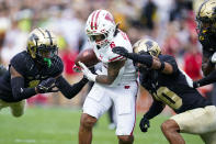 Wisconsin running back Chez Mellusi (6) is tackled by Purdue cornerback Dedrick Mackey (1) and safety Cam Allen (10) during the first half of an NCAA college football game in West Lafayette, Ind., Saturday, Oct. 23, 2021. (AP Photo/Michael Conroy)