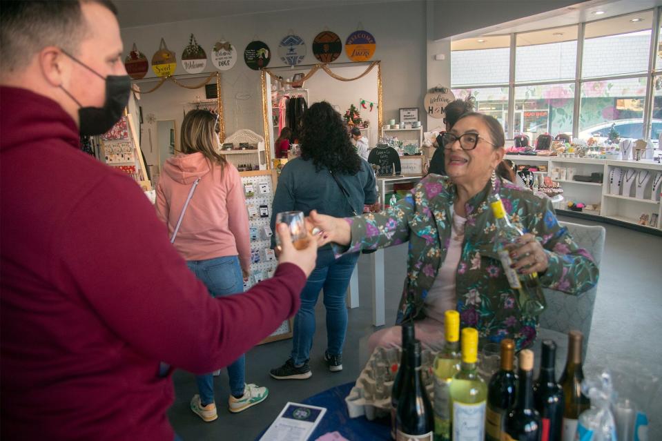 (11/27/21) Pat Brown, right, hands a glass of wine to customer Robert Van Denburgh at the Sweet Life Boutique during the Miracle MIle's Sip and Stroll wine tasting/shopping event in Stockton. CLIFFORD OTO/THE STOCKTON RECORD