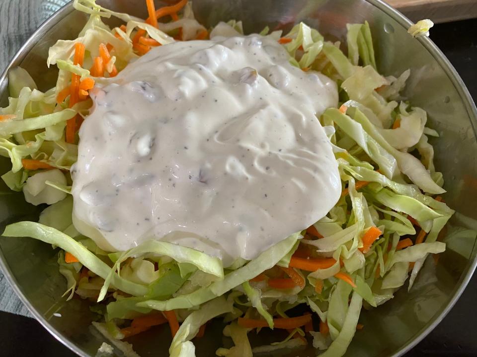 Cut up cabbage with dressing on top in a bowl.