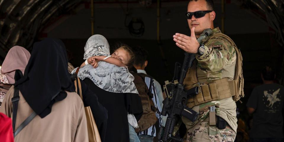 A U.S. Air Force Airman guides evacuees aboard a U.S. Air Force C-17 Globemaster III at Hamid Karzai International Airport in Kabul, Afghanistan, Tuesday, Aug. 24, 2021.