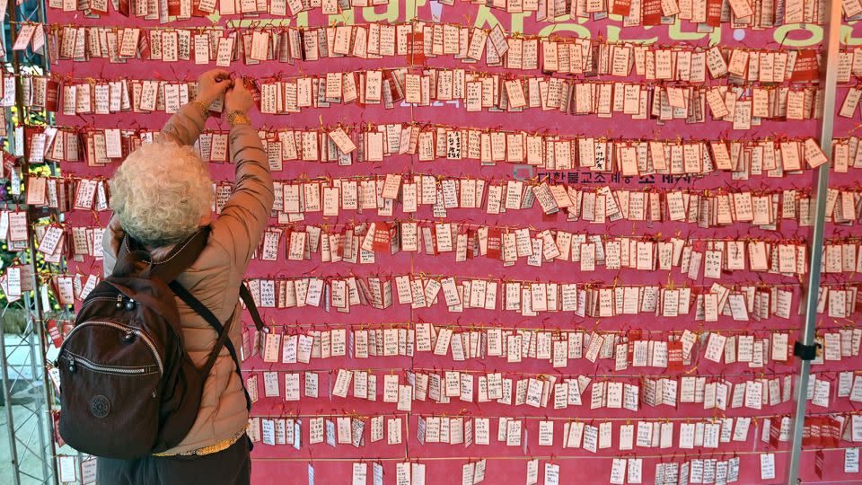 A woman attaches a name card wishing for good results for students in South Korea's college entrance exam, at a temple in Seoul on November 18, 2021.  - Jung Yeon-je/AFP/Getty Images/File