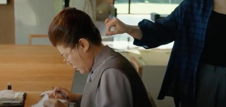 A woman reading whilst another woman is secretly putting peach shavings on her neck. A scene from Parasite